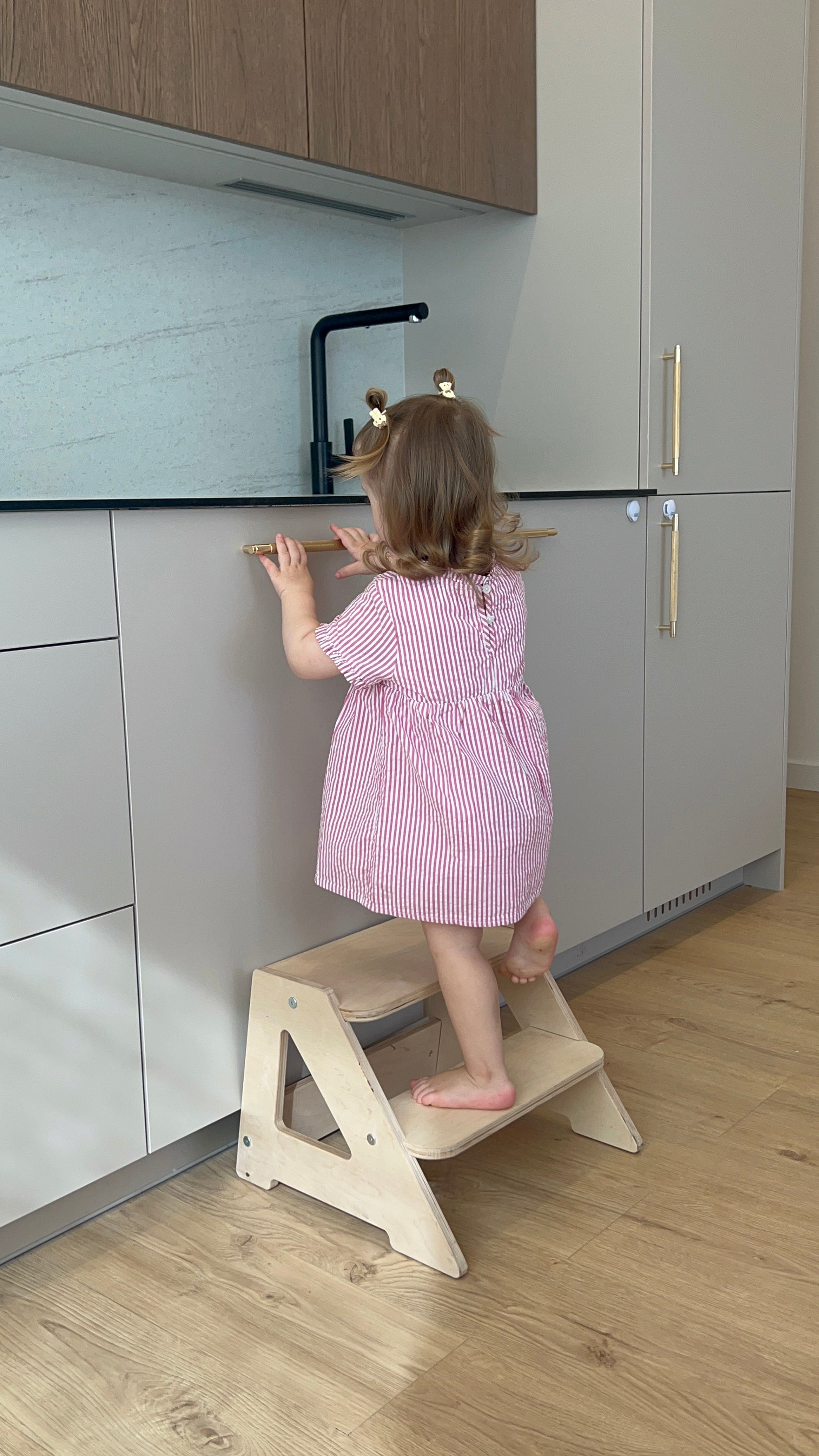 Vaikas naudoja Montessori bokštelį virtuvėje savarankiškai